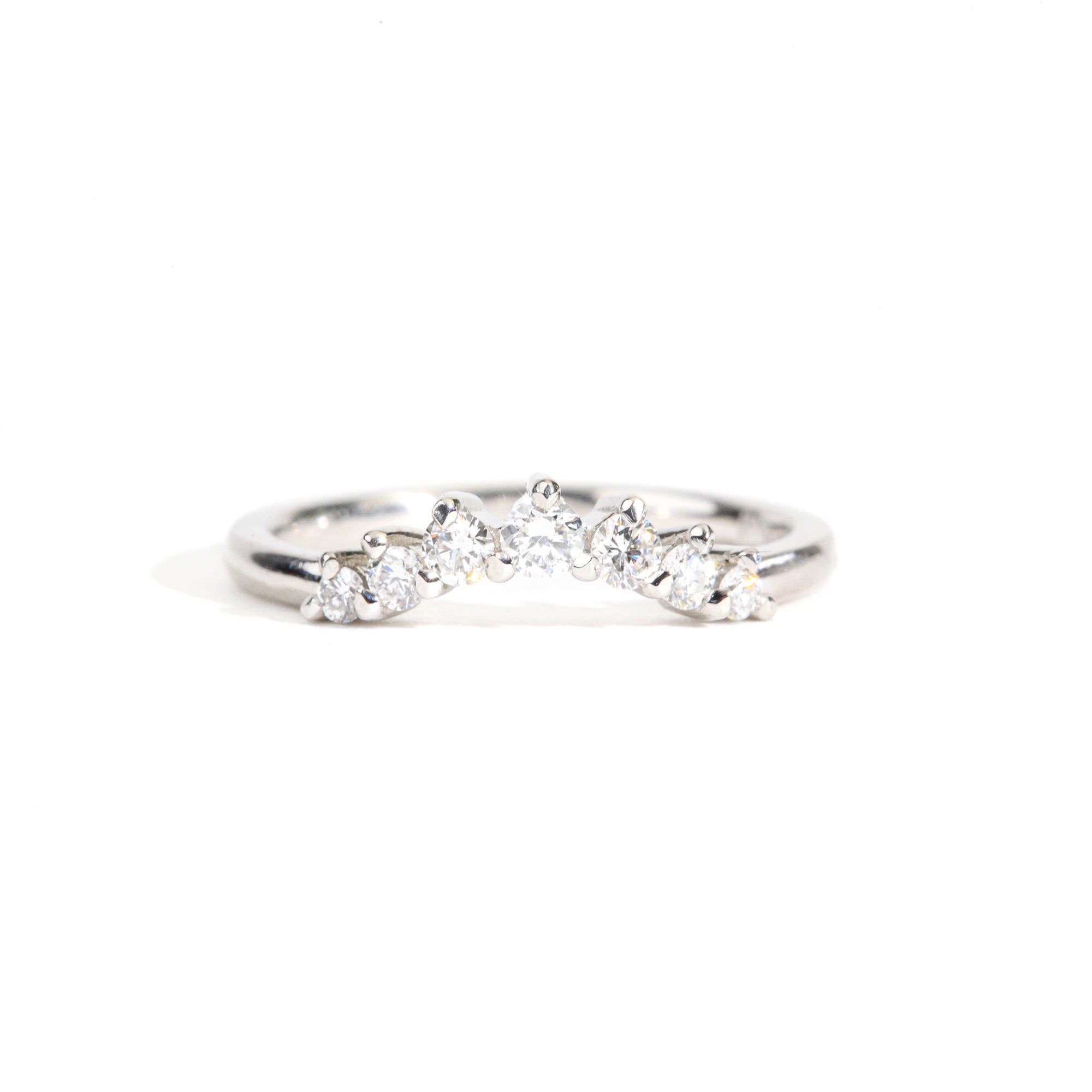 18 carat white gold woman's wedding band with 7 round white diamonds, claw set in a slight curve.