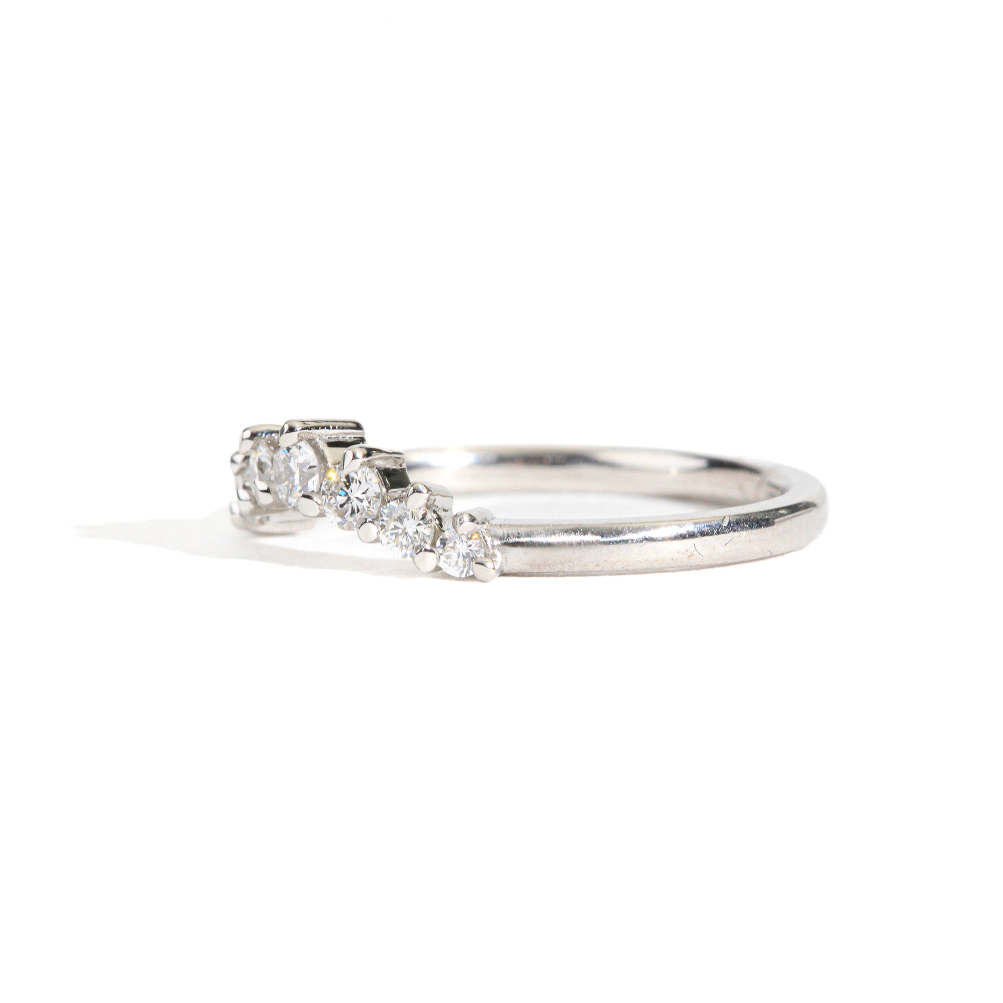18 carat white gold woman's wedding band with 7 round white diamonds, claw set in a slight curve.