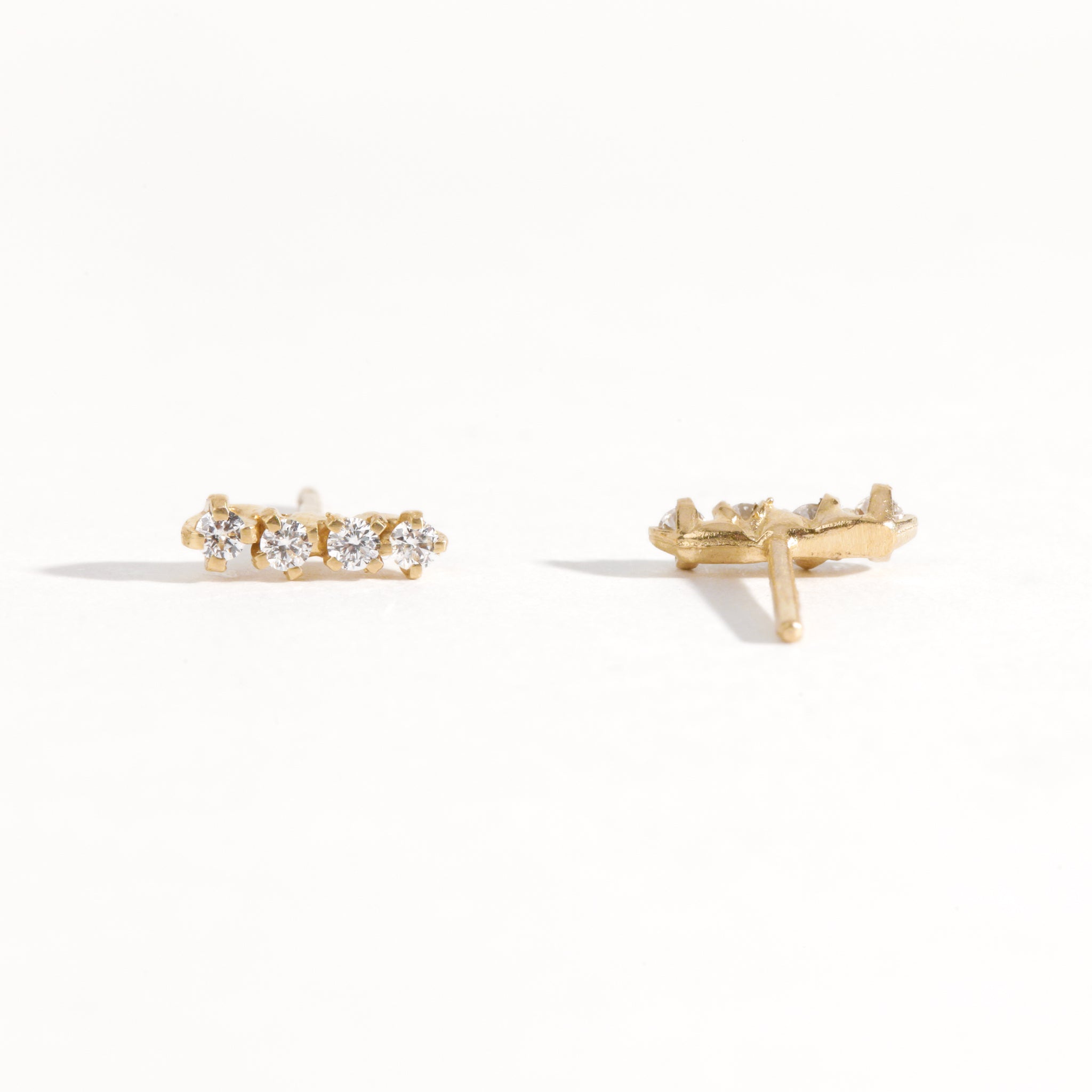 A pair of earring studs crafted with 9ct recycled refined yellow gold with a row of four diamonds by Black Finch Jewellery