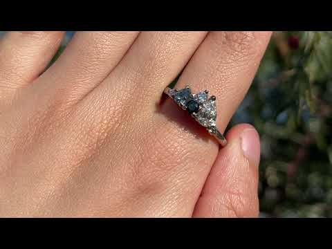 Bespoke cluster ring shown in 18 carat white gold, featuring champagne, white and pink diamonds and sapphires, shown on the hand.